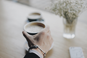 Man placing coffee on a desk.