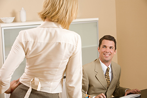 Man sitting at desk smiling at woman coworker