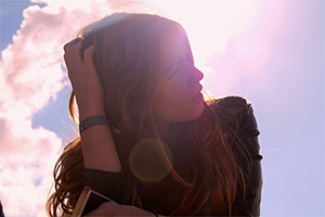 Headshot of girl looking into the sun.