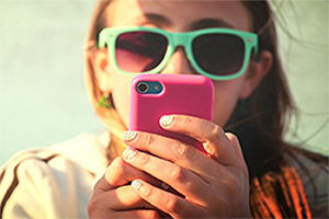 Girl wearing sunglasses texting on her pink phone