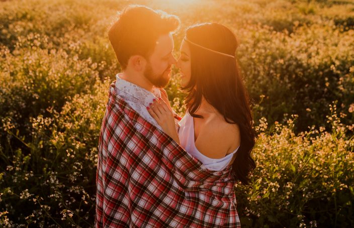 A couple embracing in a field of flowers during a sunset