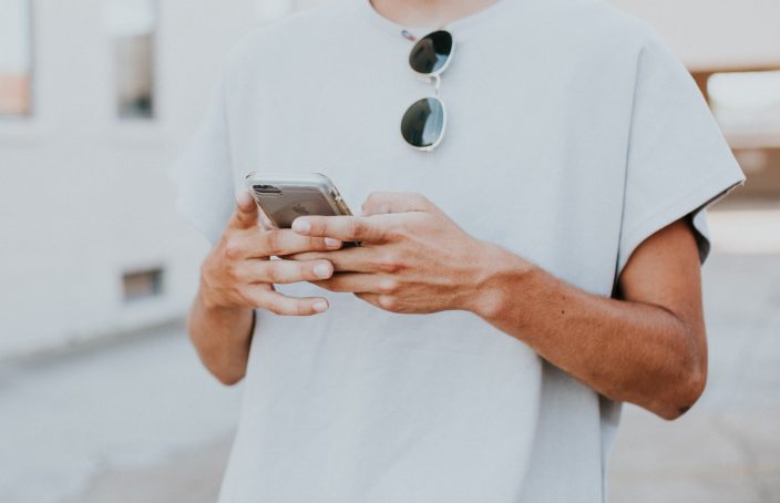 Man in white shirt holding his phone