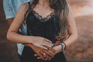 Woman holding man's hands around her waist