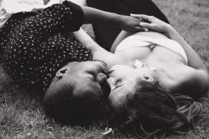 Couple laying in the grass intimately kissing