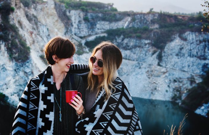 Two women chatting outdoors with blanket wrapped around them.