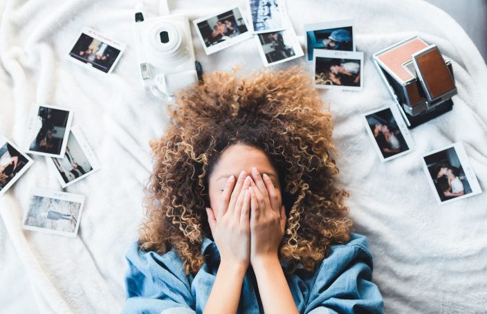 woman laying on bed surrounded by photos